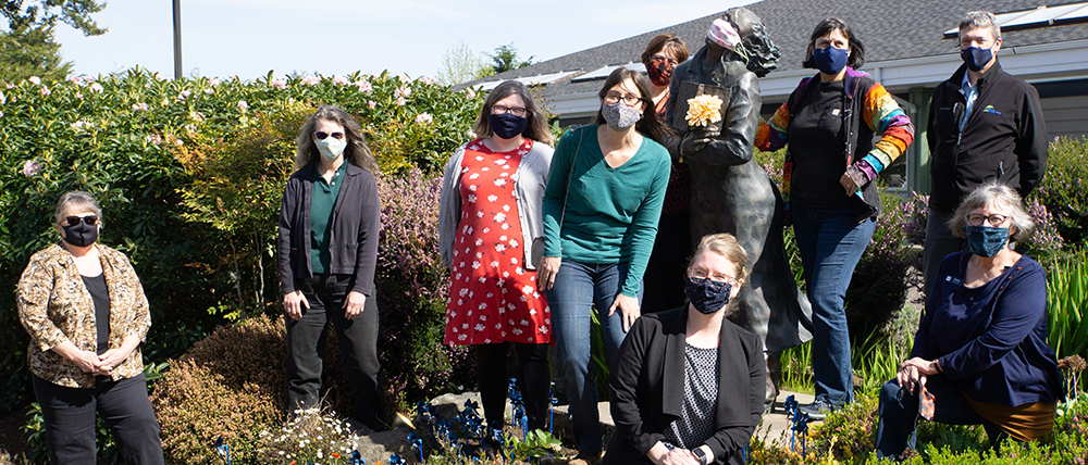 Siuslaw Vision Team members and staff gather in front of the Siuslaw Public Library, wearing masks and spaced out