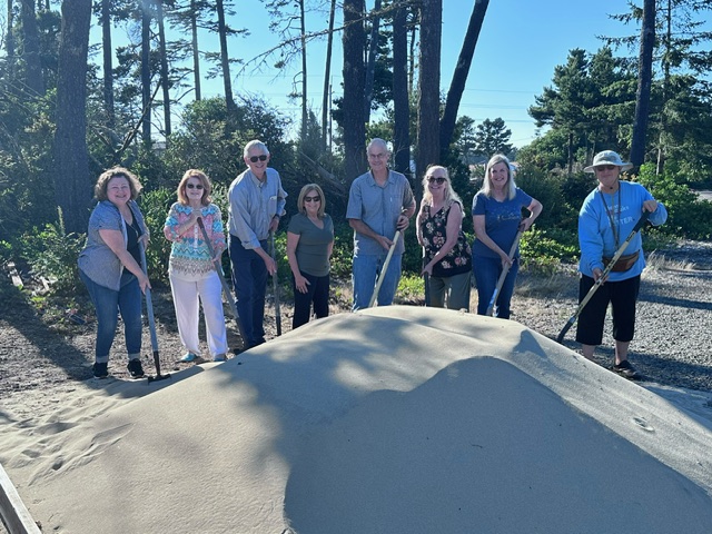 First Step Folding House groundbreaking photo. Board members and volunteers digging into the sand. 